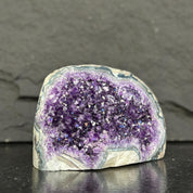 Amethyst geode on a dark surface with a gray background