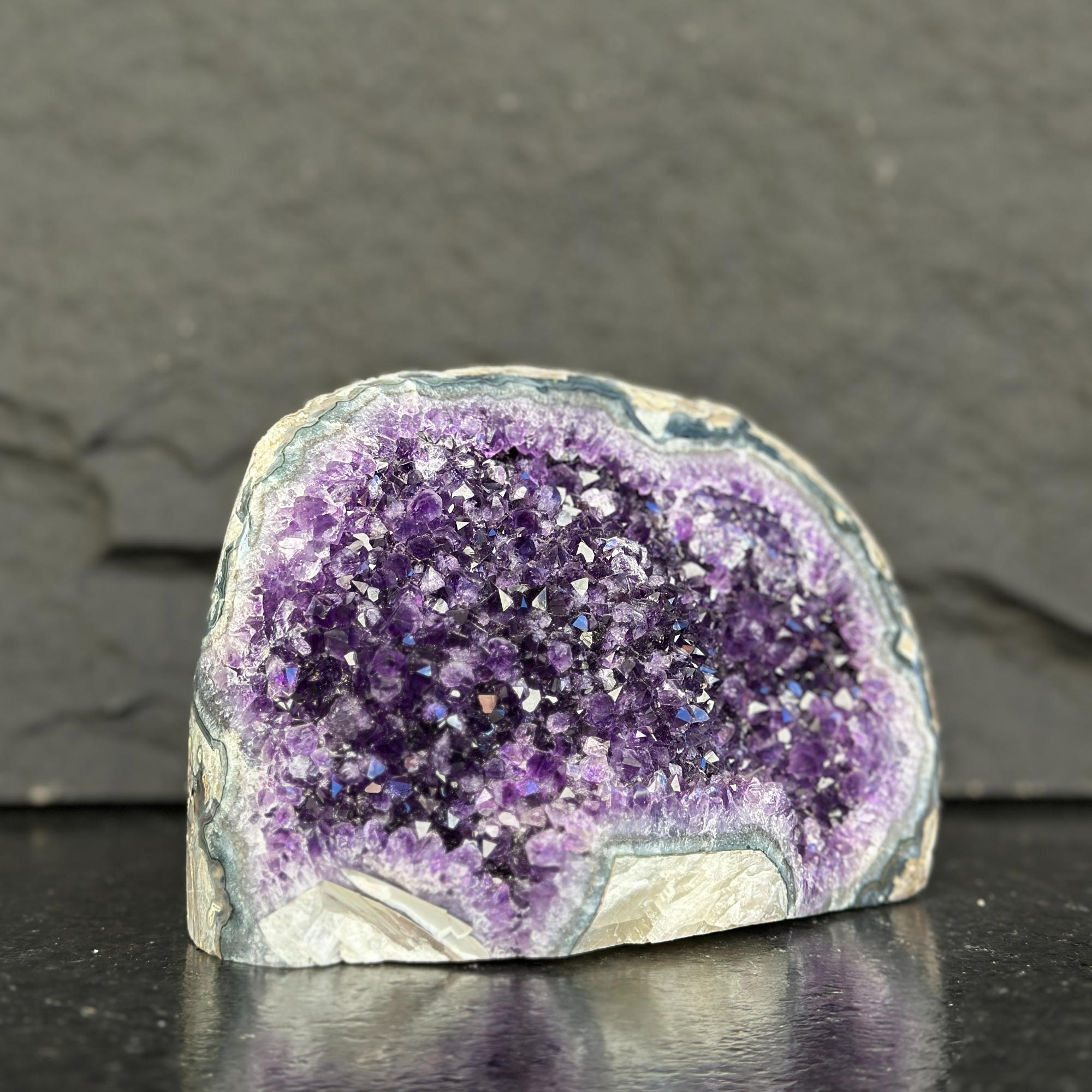 Amethyst geode on a dark surface with a gray background