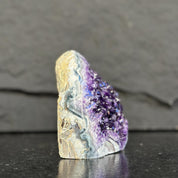 Amethyst geode on a dark surface with a gray background