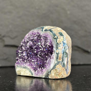 Geode with purple interior and textured surface on a dark background