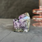 Polished amethyst crystal on a dark surface with a blurred background