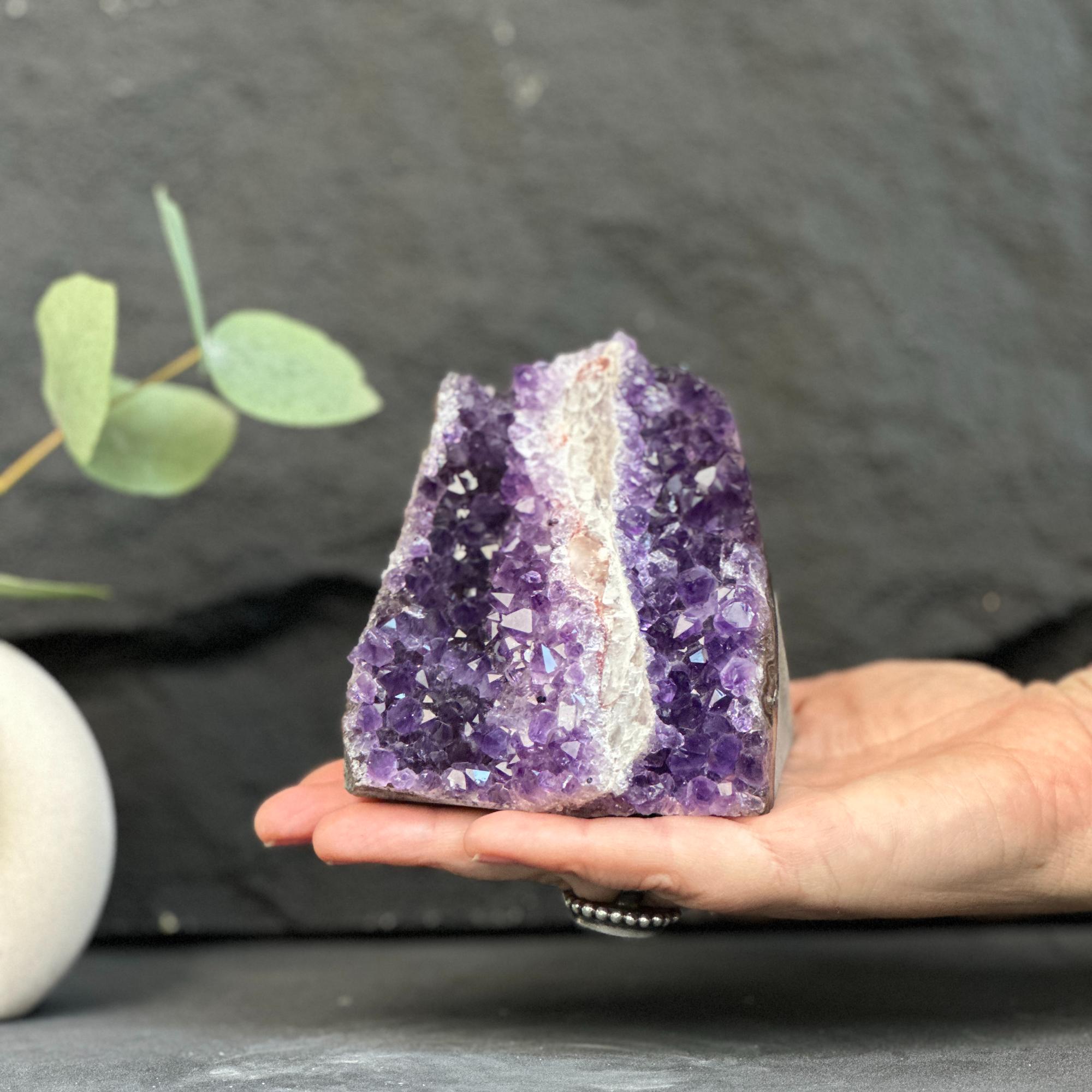 Hand holding a large amethyst crystal with a dark background