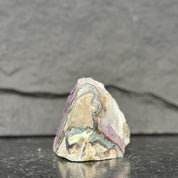 unpolished stone with multicolored patterns on a dark surface