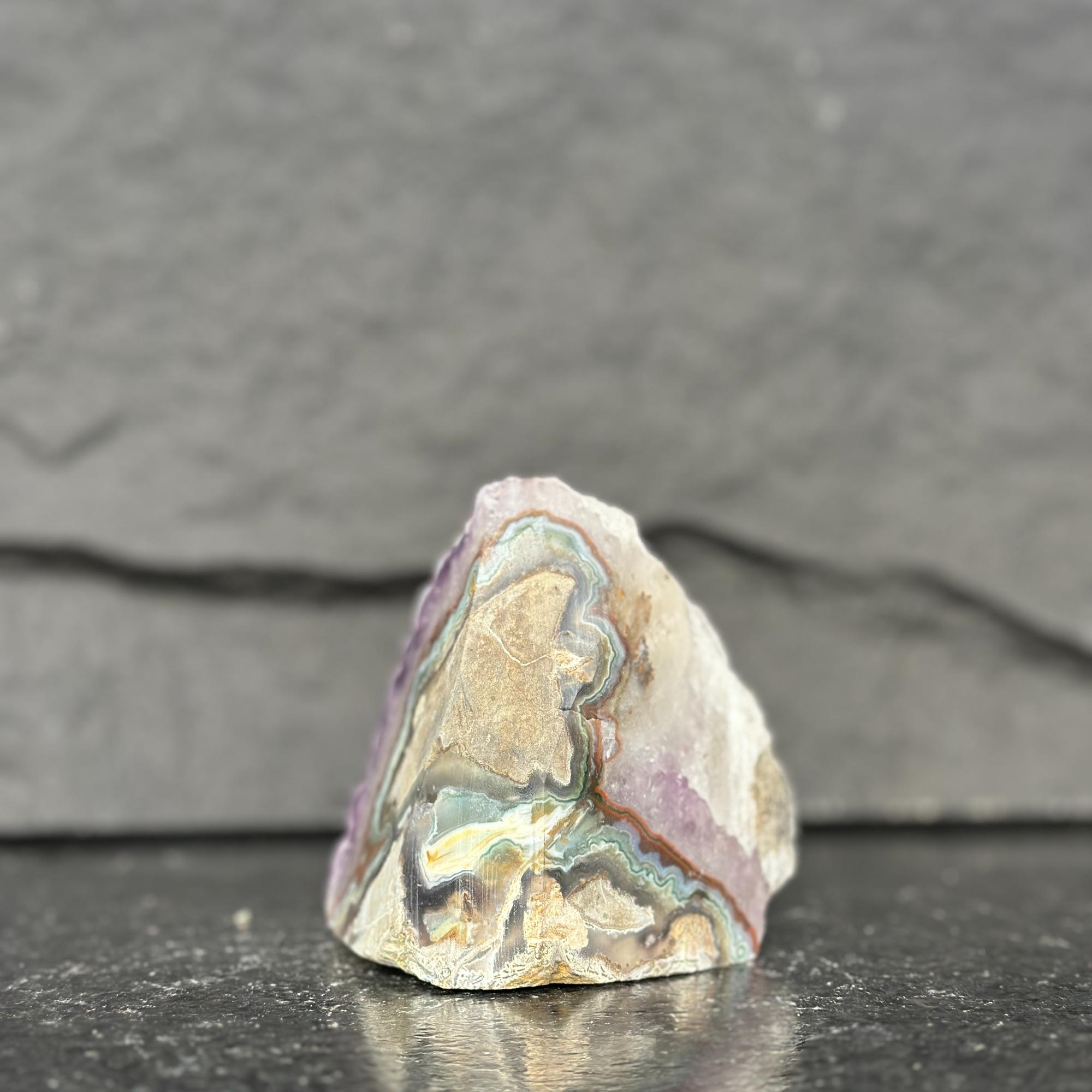 unpolished stone with multicolored patterns on a dark surface