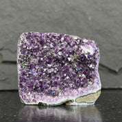 Amethyst crystal on a dark surface with a gray background