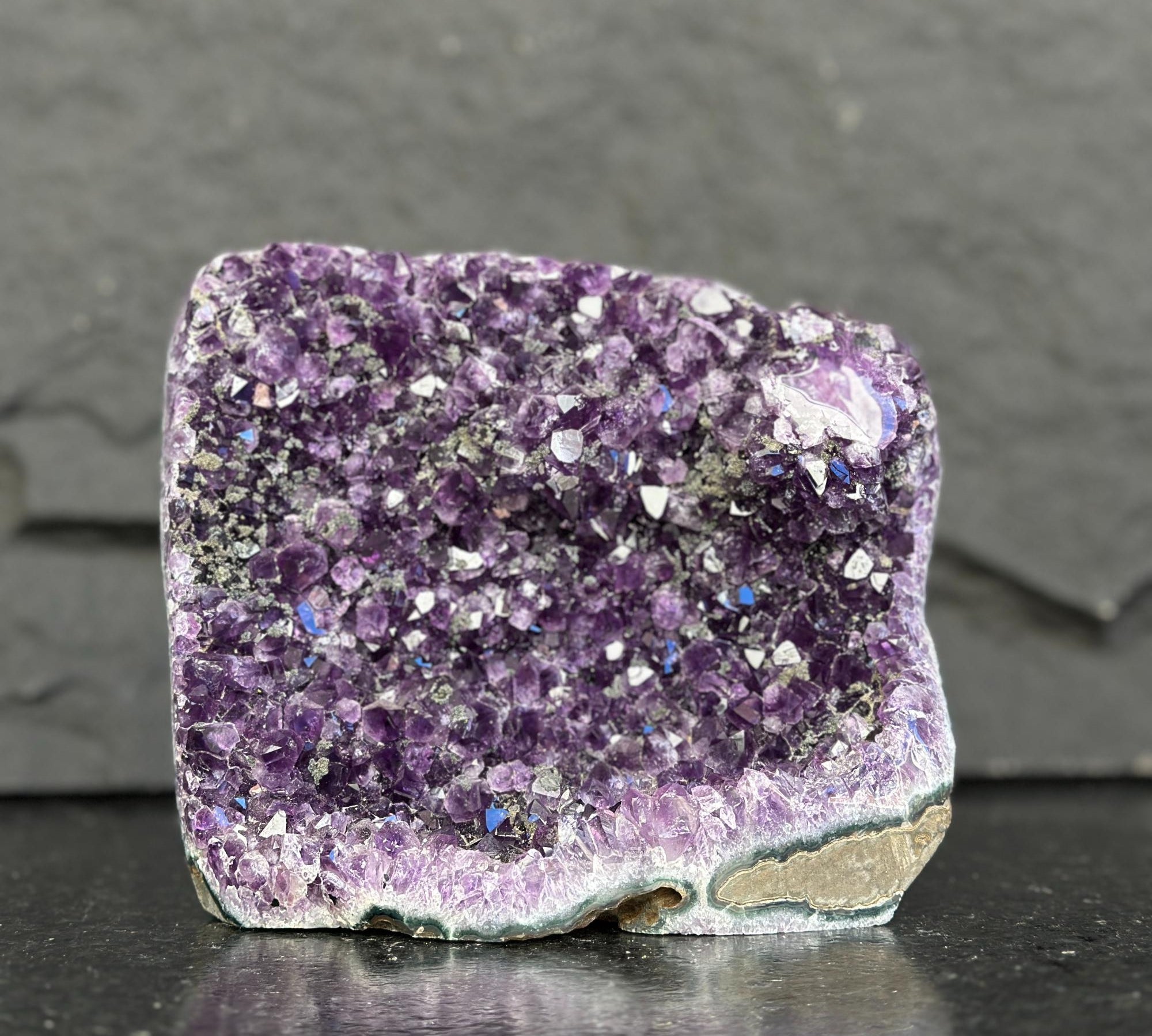Amethyst crystal on a dark surface with a gray background
