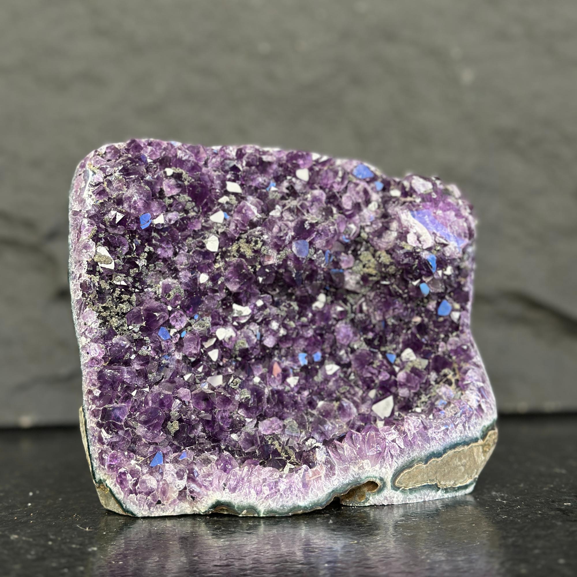 Purple crystal rock on a dark surface with a gray background