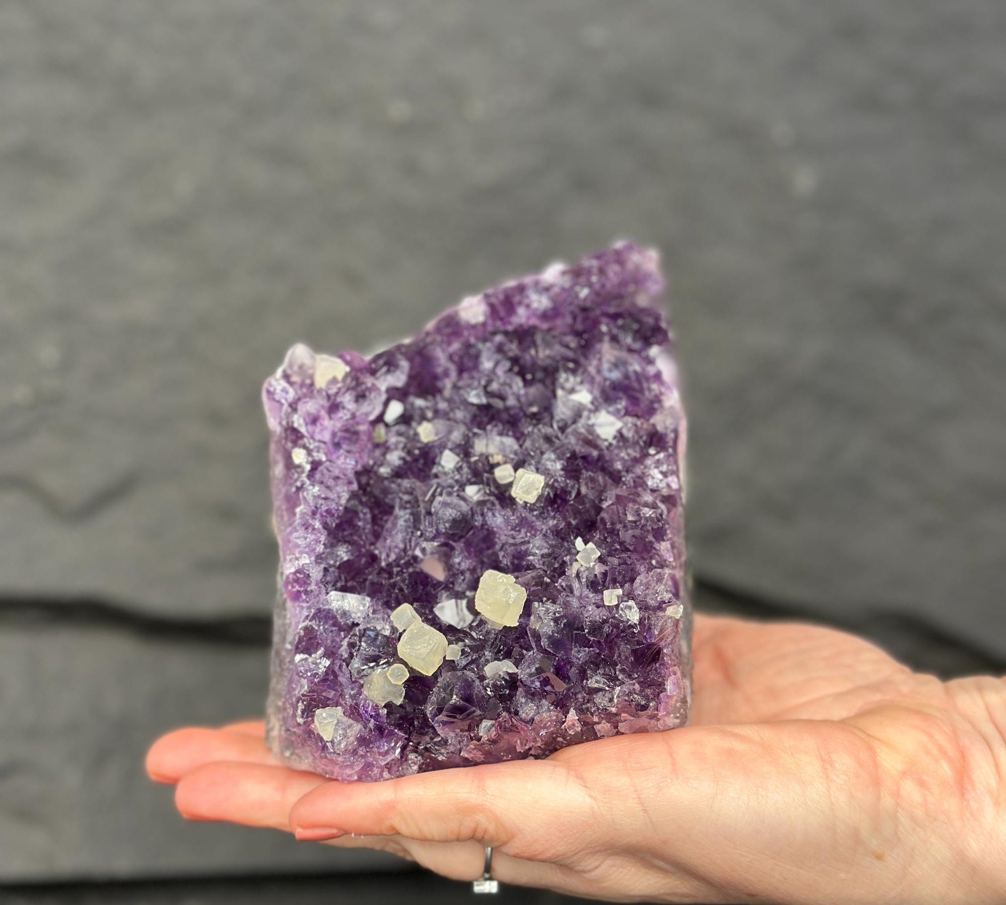 Hand holding a large purple crystal against a dark background