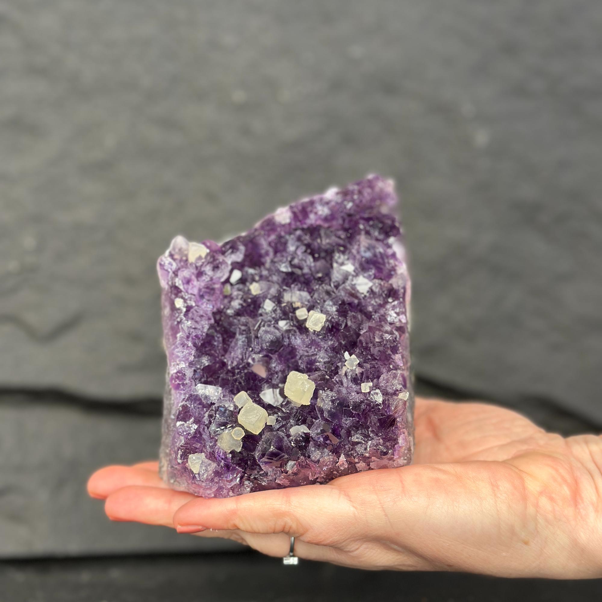 Hand holding a large purple crystal against a dark background