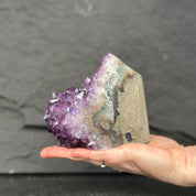 Hand holding a large amethyst crystal against a dark background