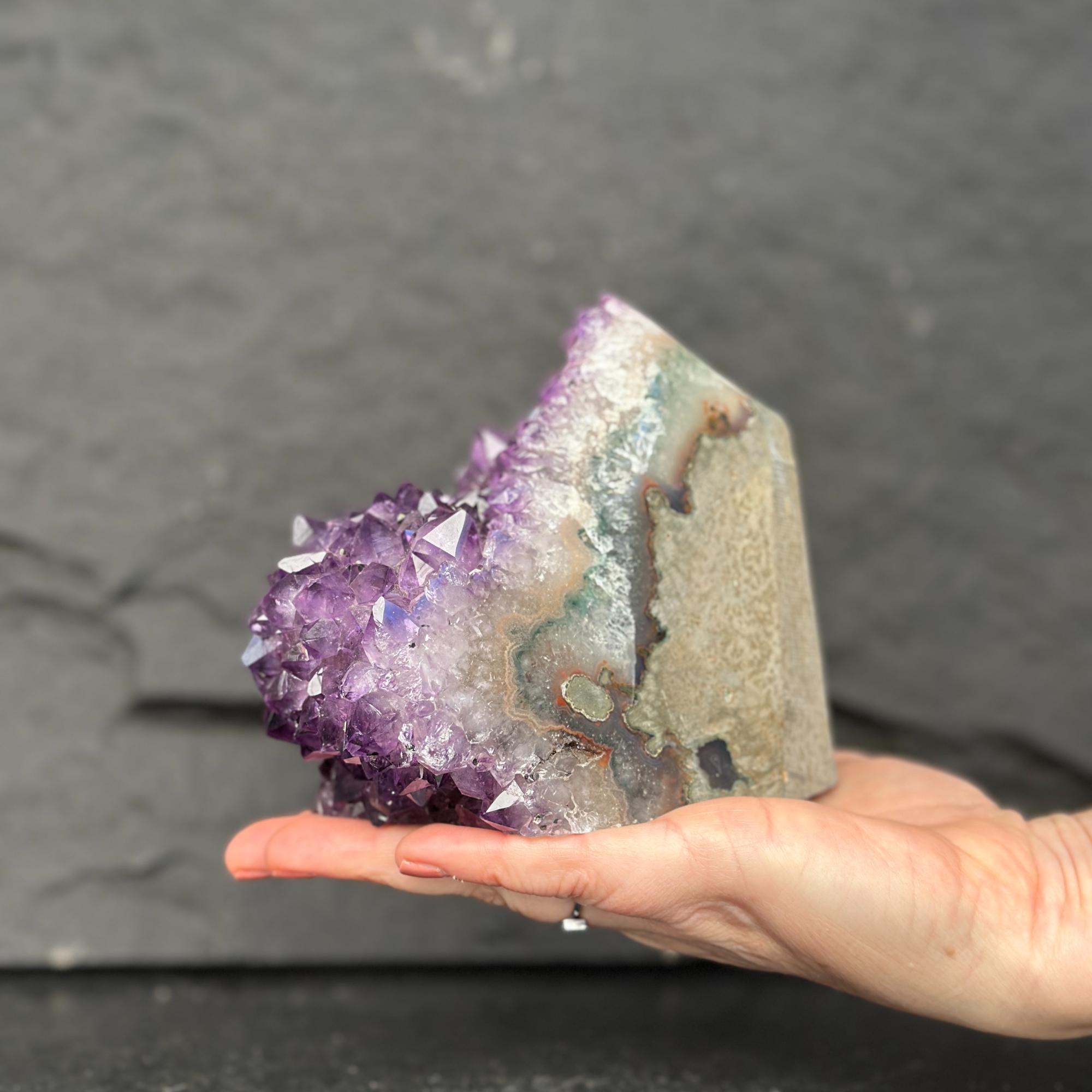 Hand holding a large amethyst crystal against a dark background