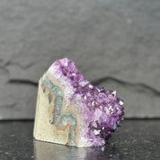 Amethyst crystal on a dark surface with a gray background