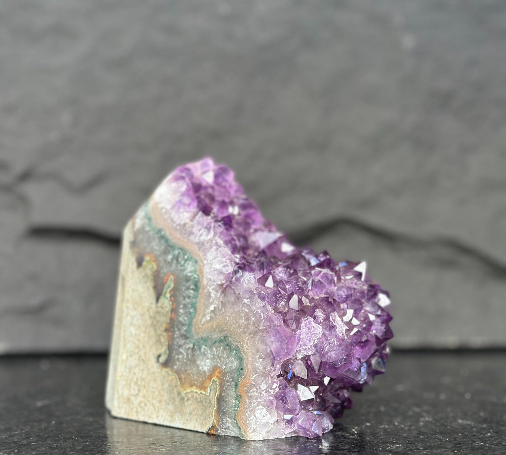 Amethyst crystal on a dark surface with a gray background