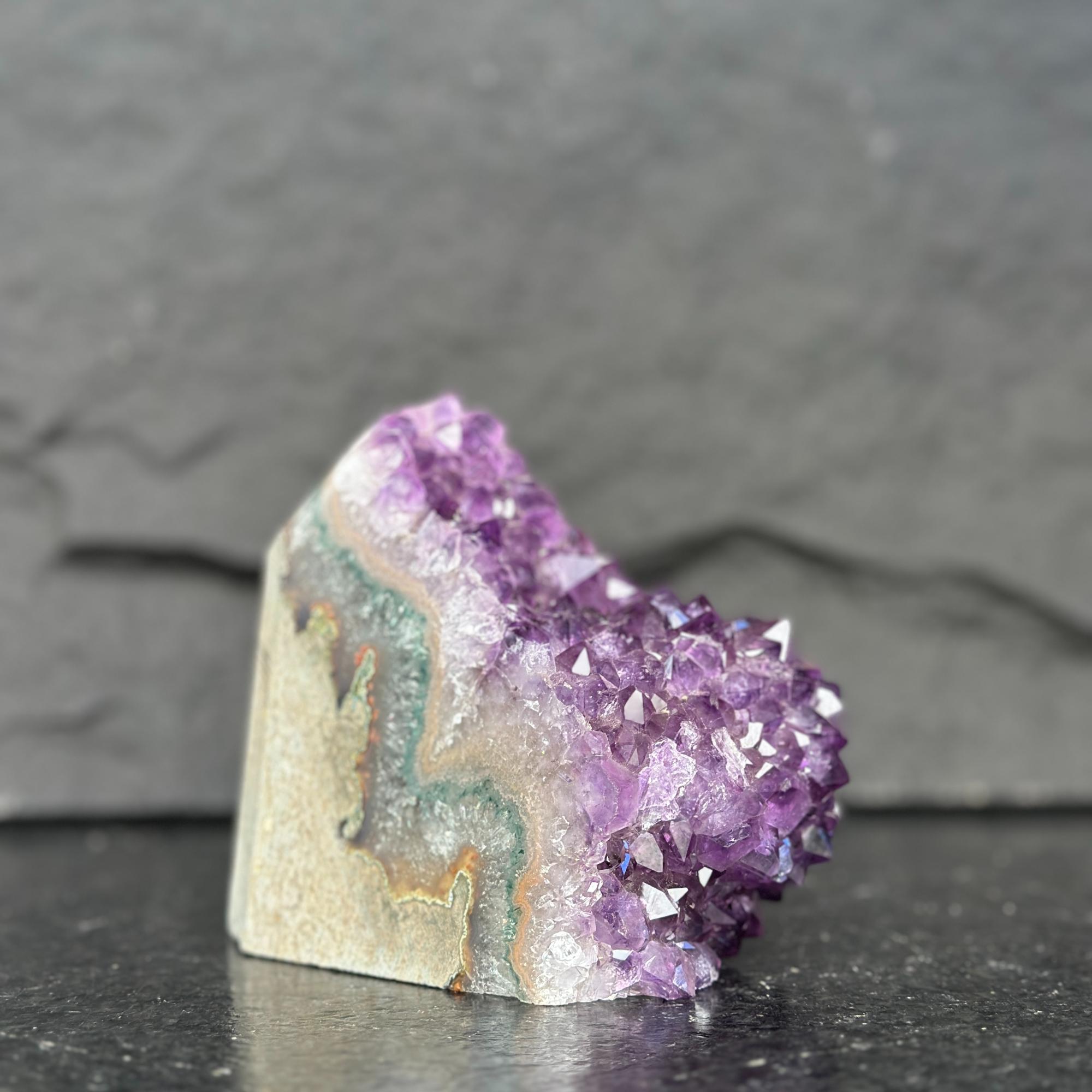 Amethyst crystal on a dark surface with a gray background
