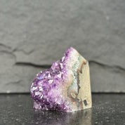 Amethyst crystal on a dark surface with a gray background