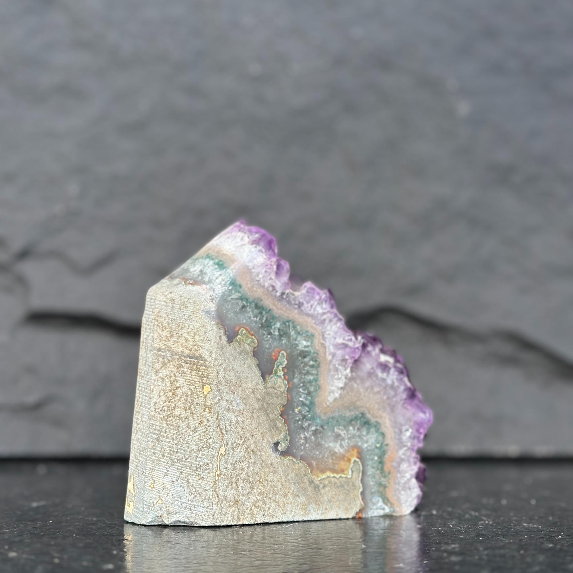 Geode crystal with purple and green colors on a dark background