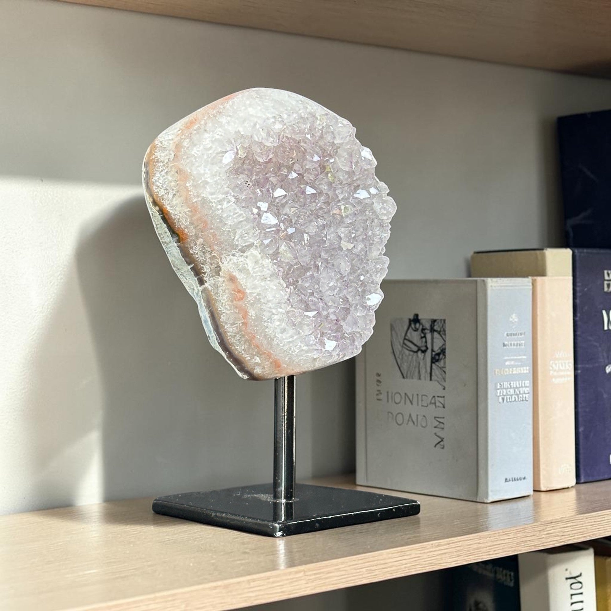 Geode crystal on a stand on a shelf with books in the background