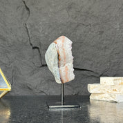 Geological specimen on a stand against a dark stone background
