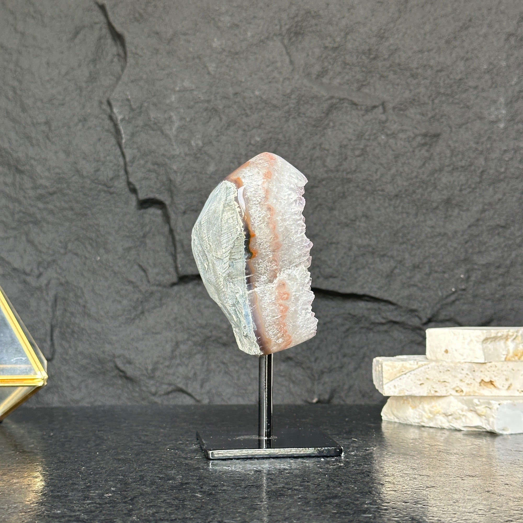 Geological specimen on a stand against a dark stone background