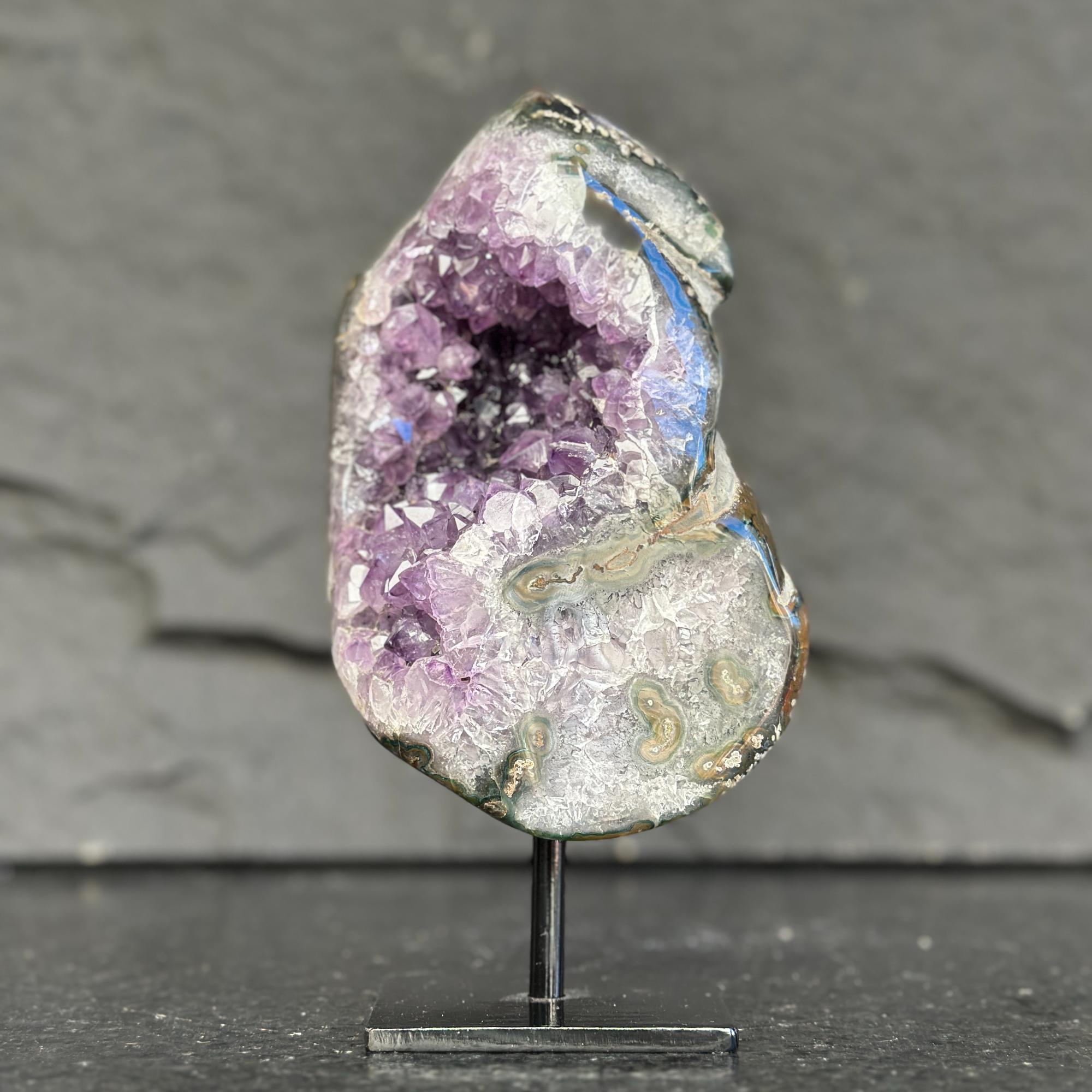 Amethyst geode on a stand against a dark background