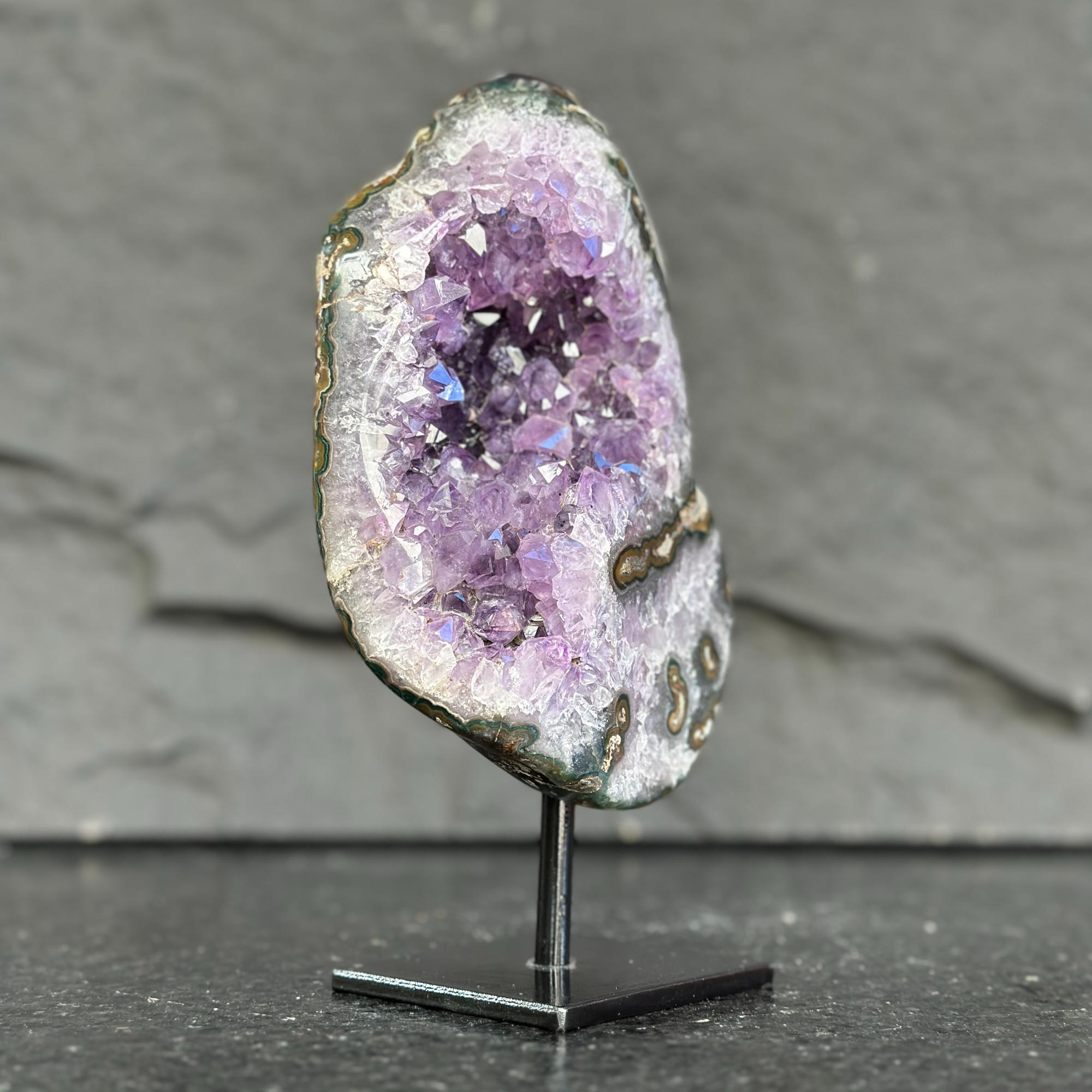 Amethyst geode on a stand against a gray background