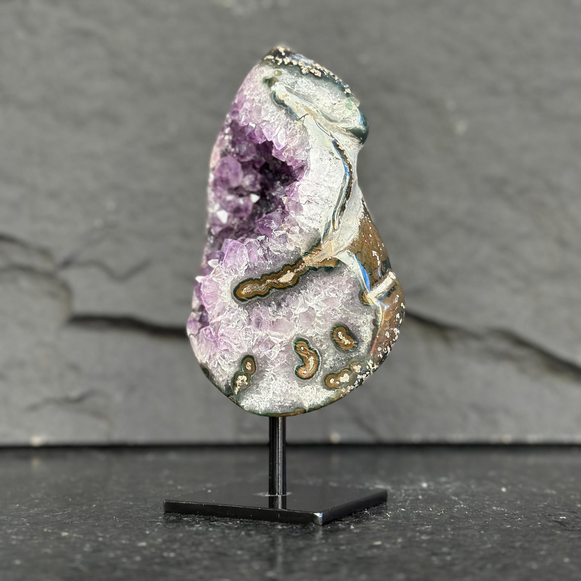 Amethyst crystal on a stand against a dark background
