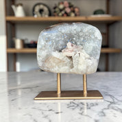 Geode crystal on a brass stand on a marble surface with a blurred background