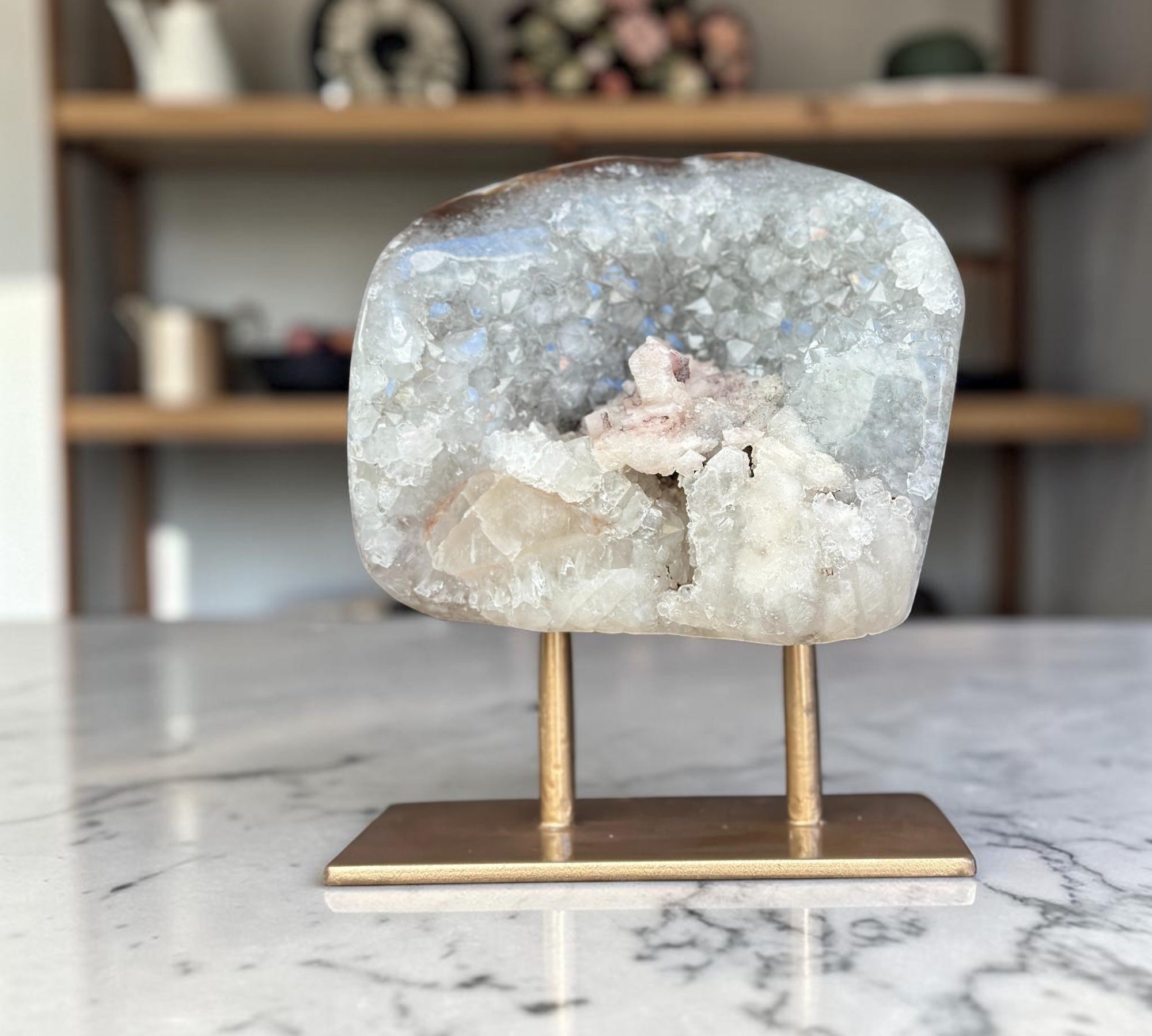 Geode crystal on a brass stand on a marble surface with a blurred background