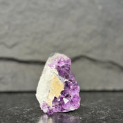 Amethyst crystal on a dark surface with a gray background