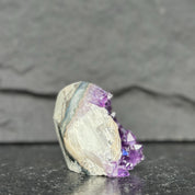Crystal with purple and white colors on a dark surface