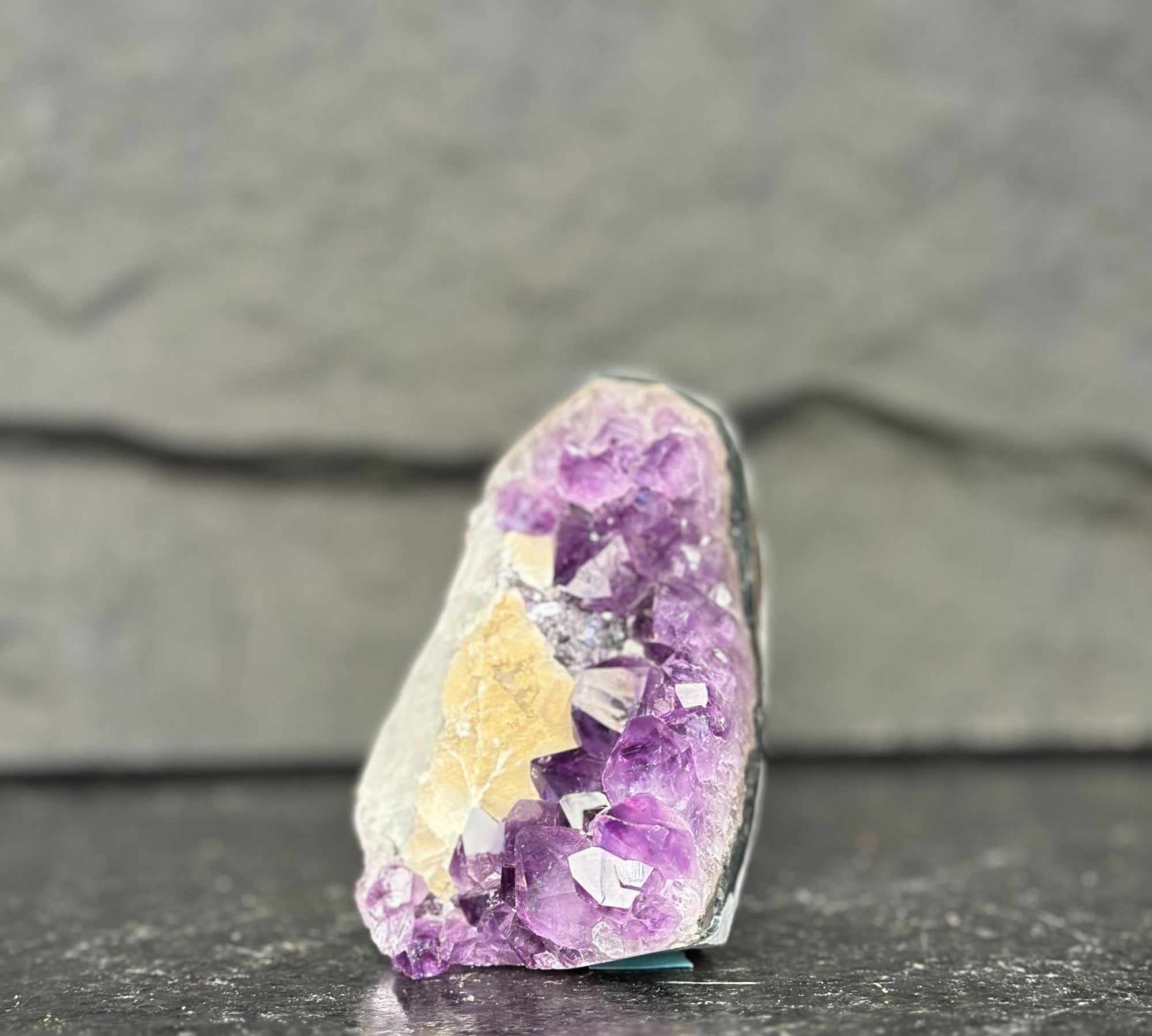 Amethyst crystal on a dark surface with a gray background