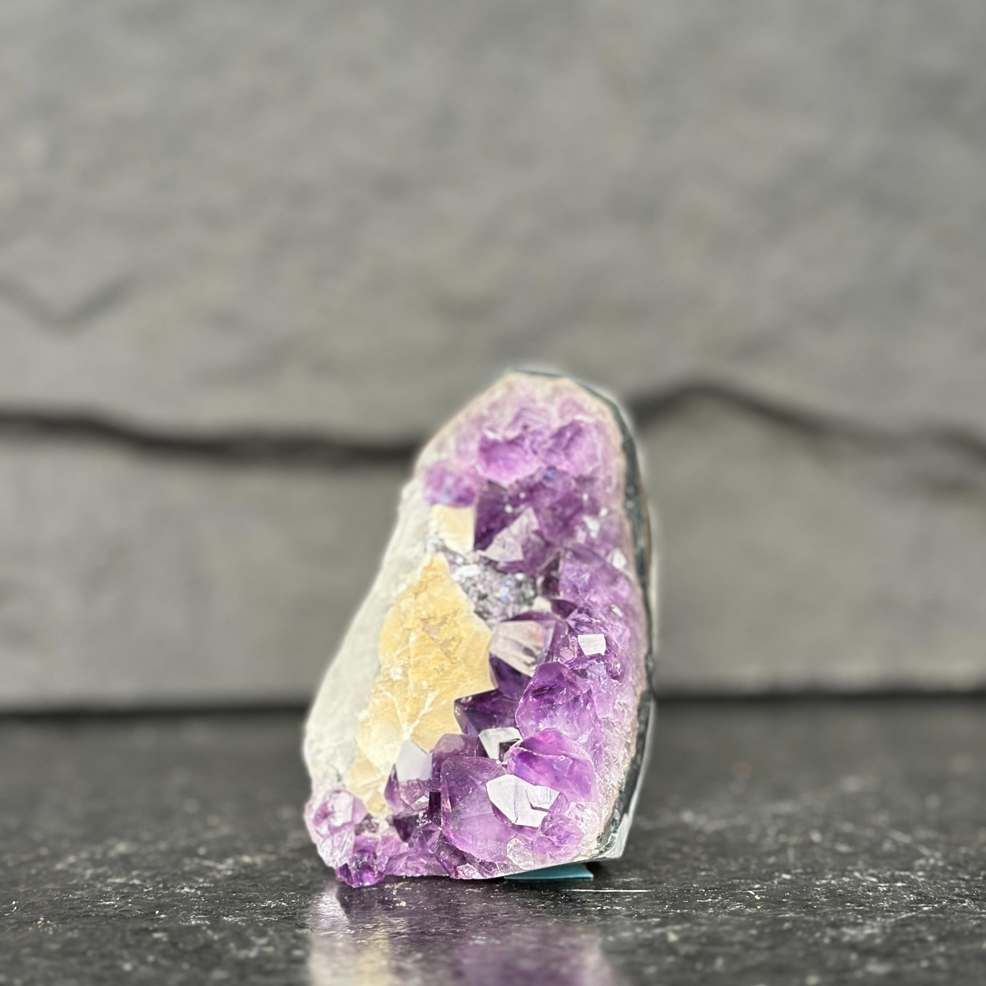 Amethyst crystal on a dark surface with a gray background