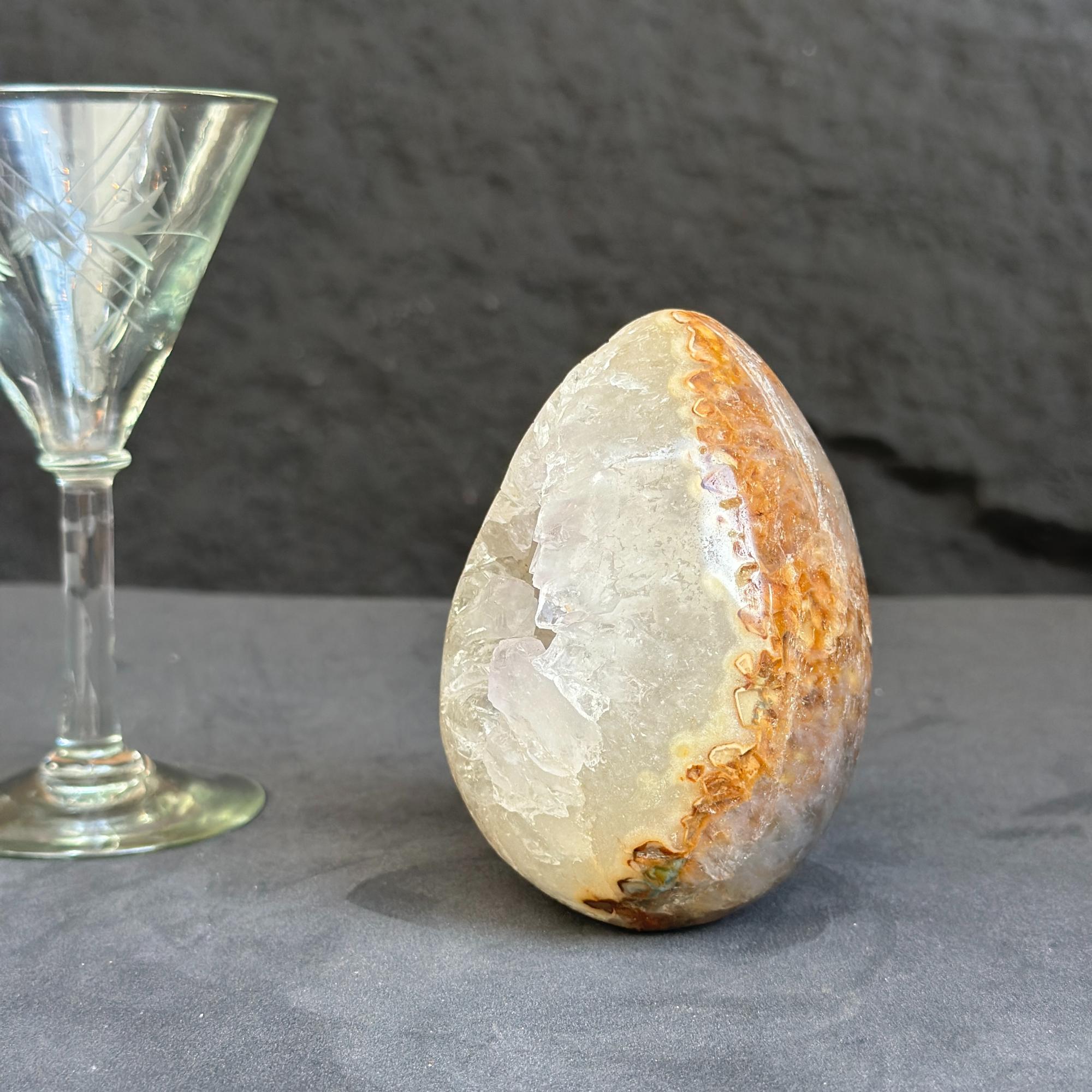 Decorative stone egg next to a glass on a dark surface