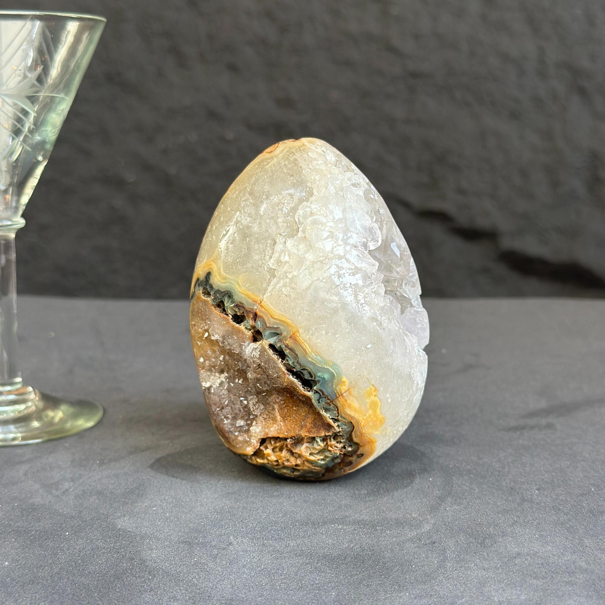 Geode crystal next to a glass goblet on a dark surface