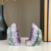 Two amethyst geode bookends with sparkling purple crystals and green-gray agate bands.