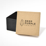 Deep Purple Project kraft box with black crystal logo and text, partially open to show black interior. Amethyst geode packaging.
